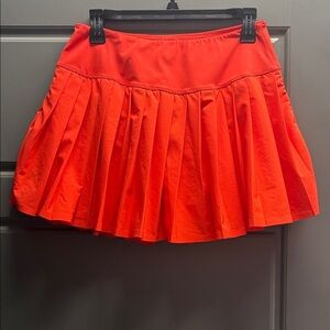 Blood Orange pleated tennis skirt with attached shorts. Spandex material.